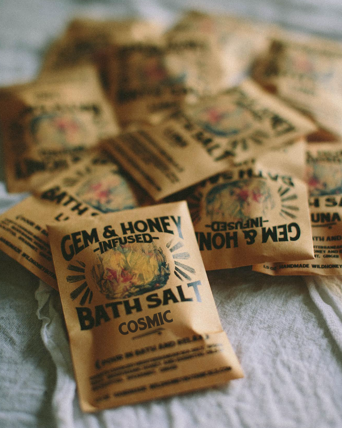 Bath salt packets with 'Gem & Honey' branding on a textured surface
