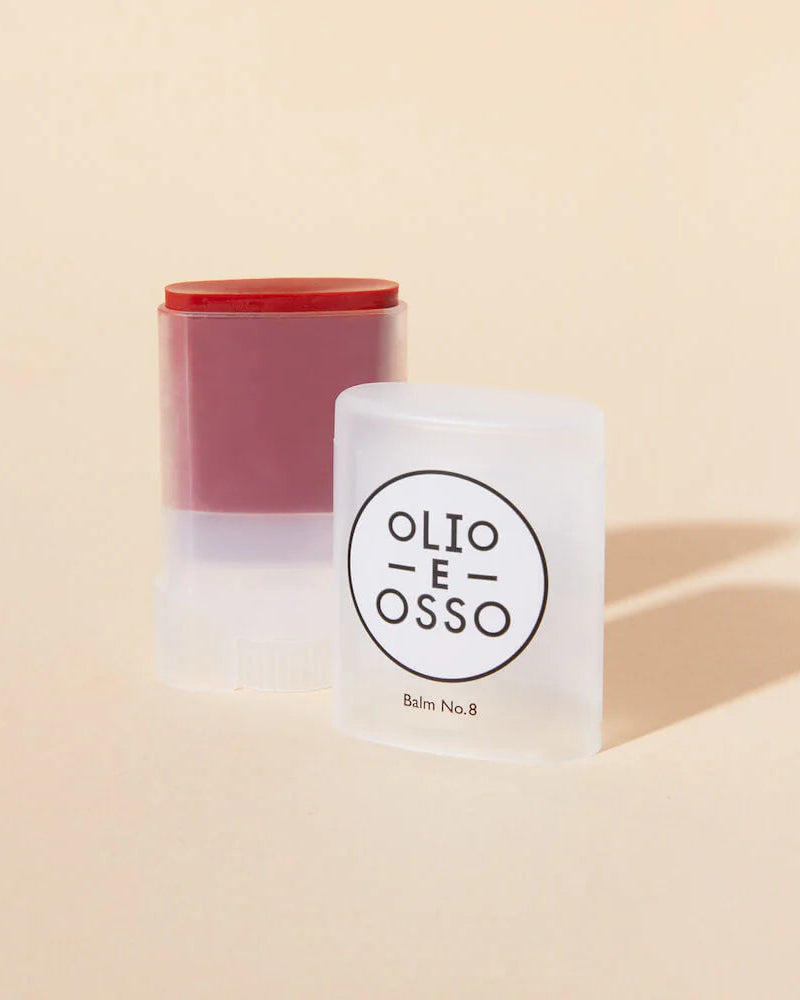 Two cylindrical containers with a red top and white body on a beige background, featuring the brand 'Olio E Osso'.