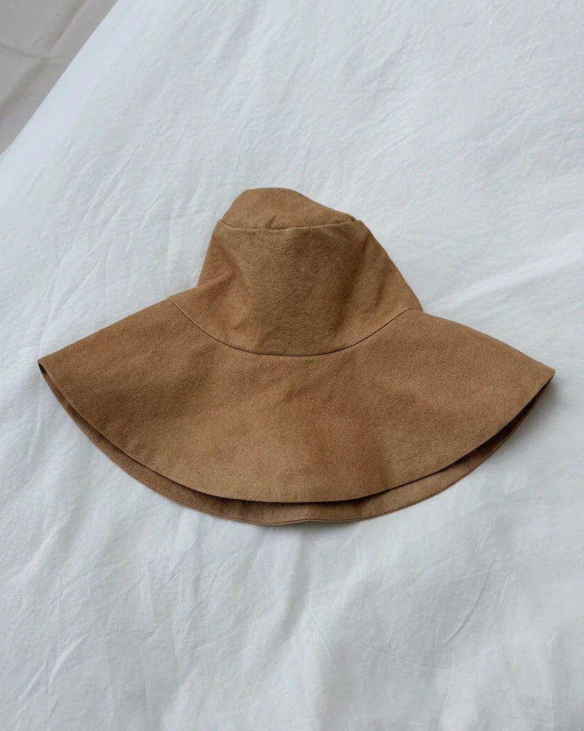 Brown wide-brimmed hat on a white fabric surface