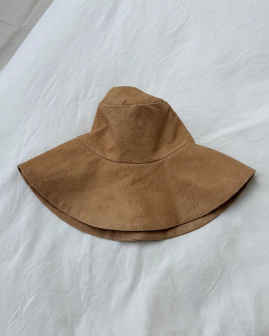 Brown wide-brimmed hat on a white fabric surface