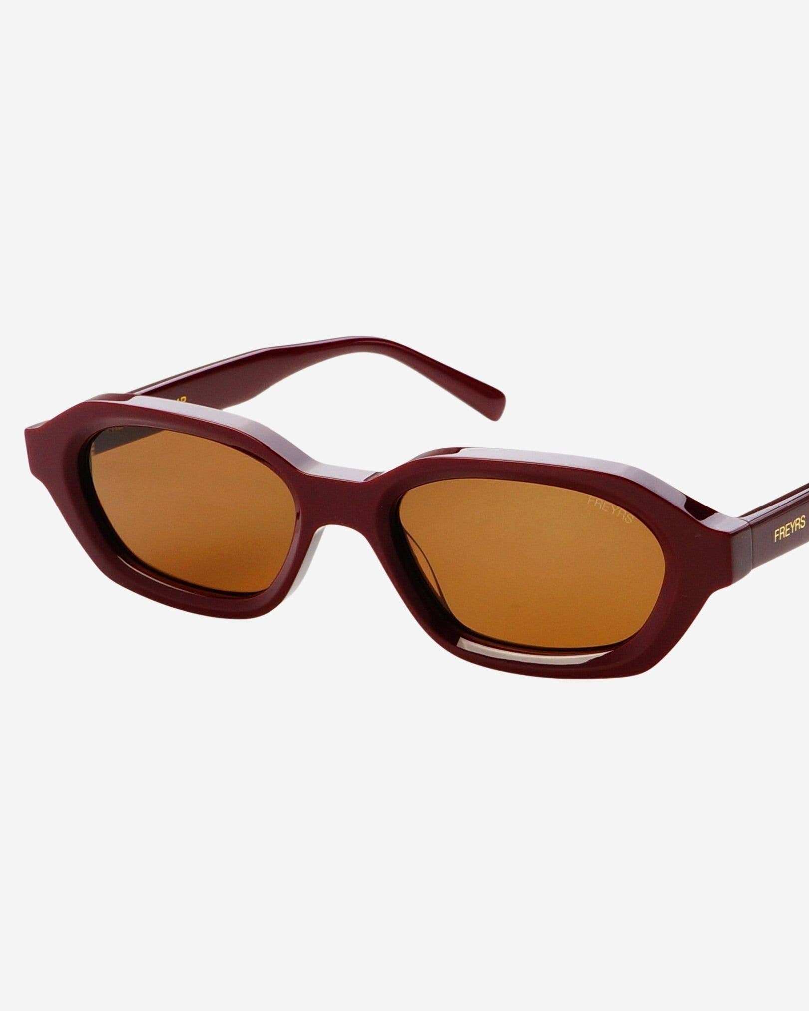 Sunglasses with brown lenses and maroon frame on a white background