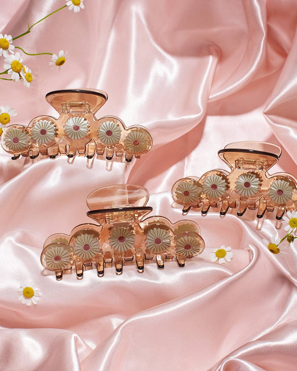 Set of decorative hair clips on a pink satin background with flowers.