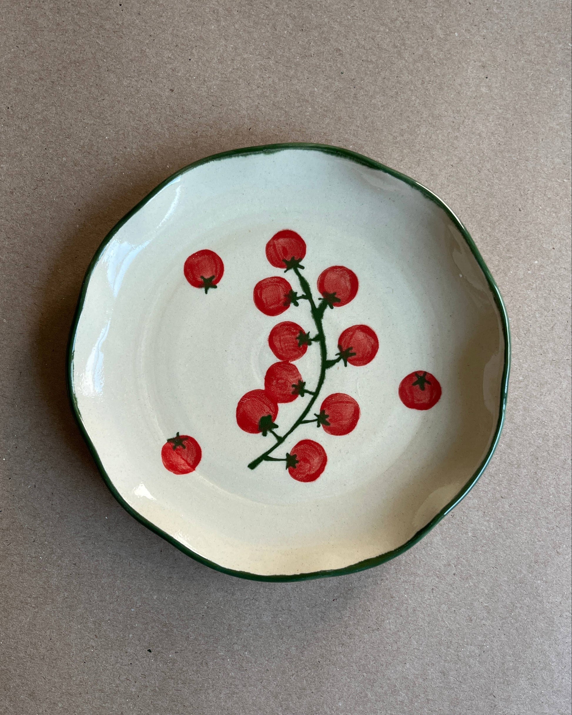 Small ceramic plate with red tomato design on a beige background