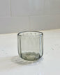 Clear glass tumbler on a white surface with a tiled wall background
