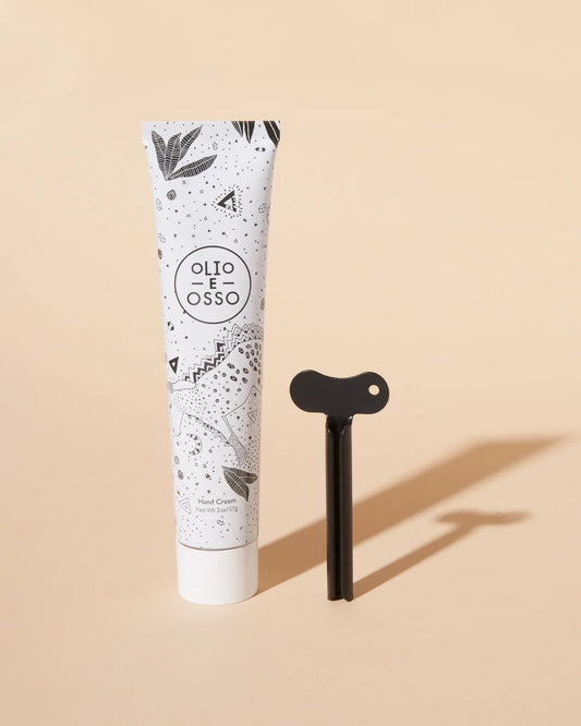 Tube of hand cream with a black tool on a beige background
