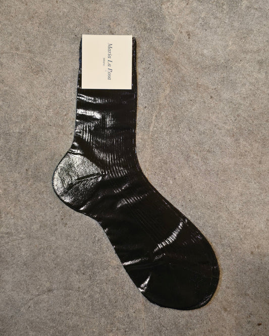 Black sock on a gray surface with a brand card underneath