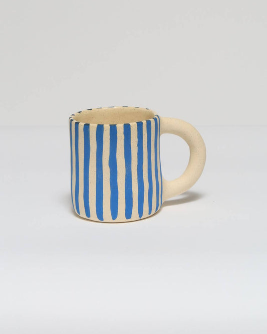 Ceramic mug with blue and white striped pattern on a light gray background