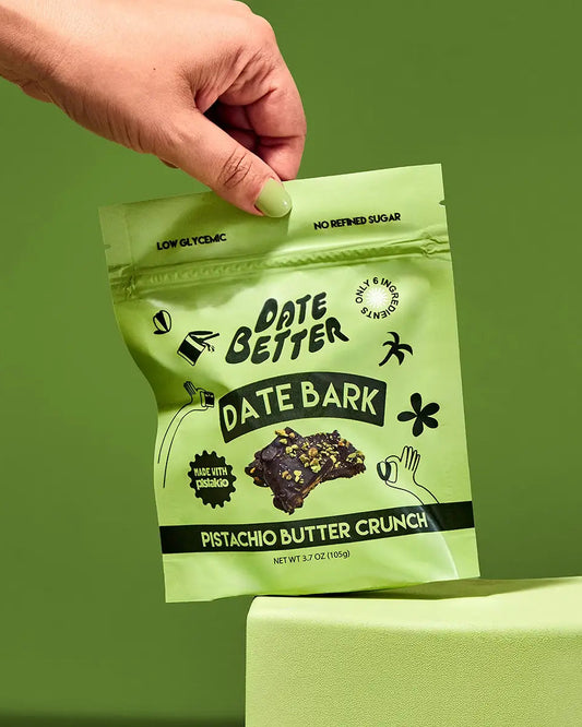Hand holding a green package of Date Better Date Bark against a green background