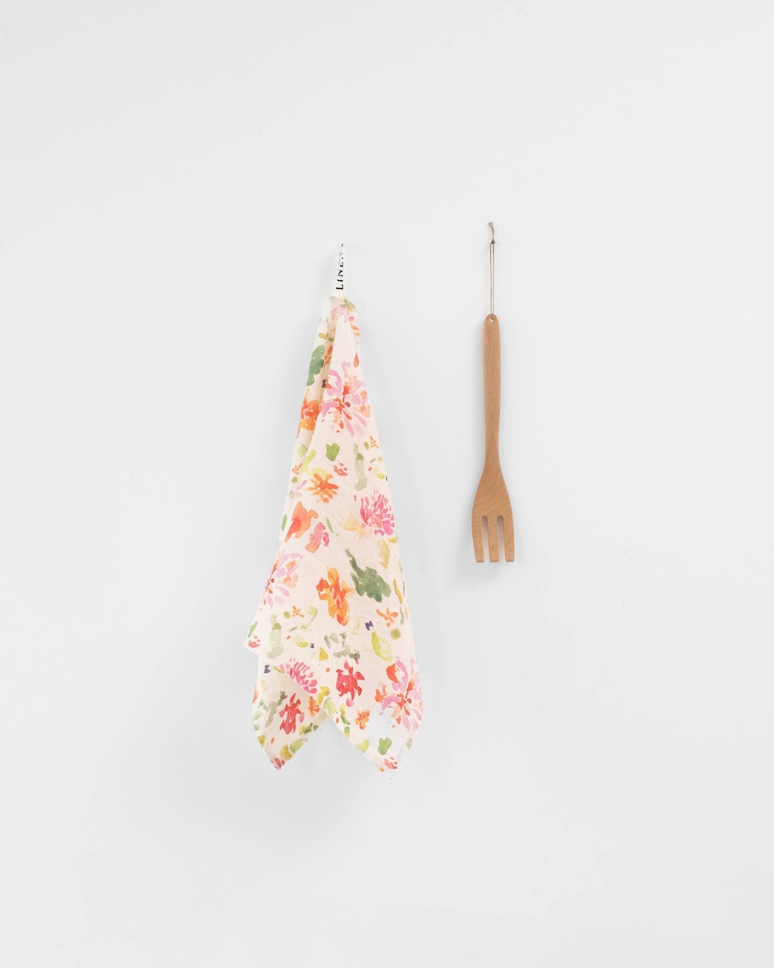 Floral kitchen towel and wooden fork on a white background