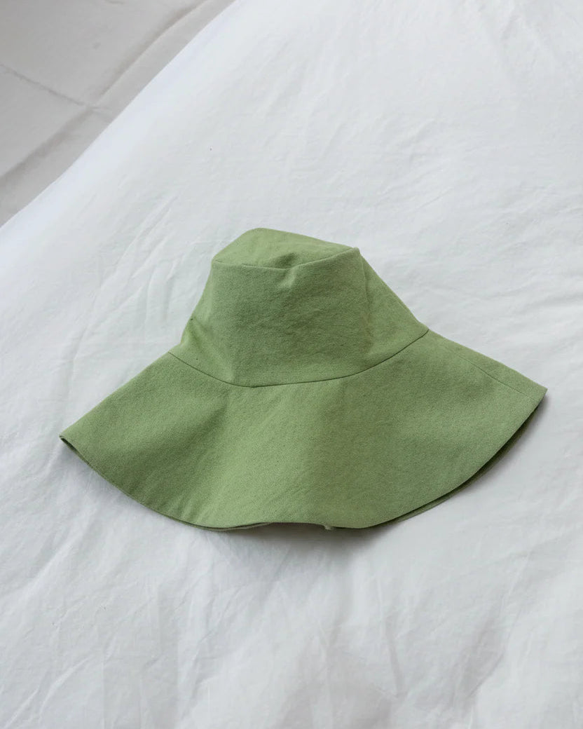 Green bucket hat on a white bedspread