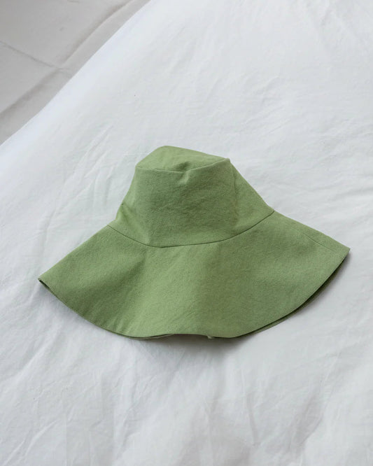 Green bucket hat on a white bedspread