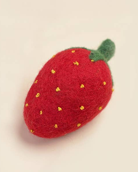 Red strawberry-shaped object with yellow seeds on a beige background