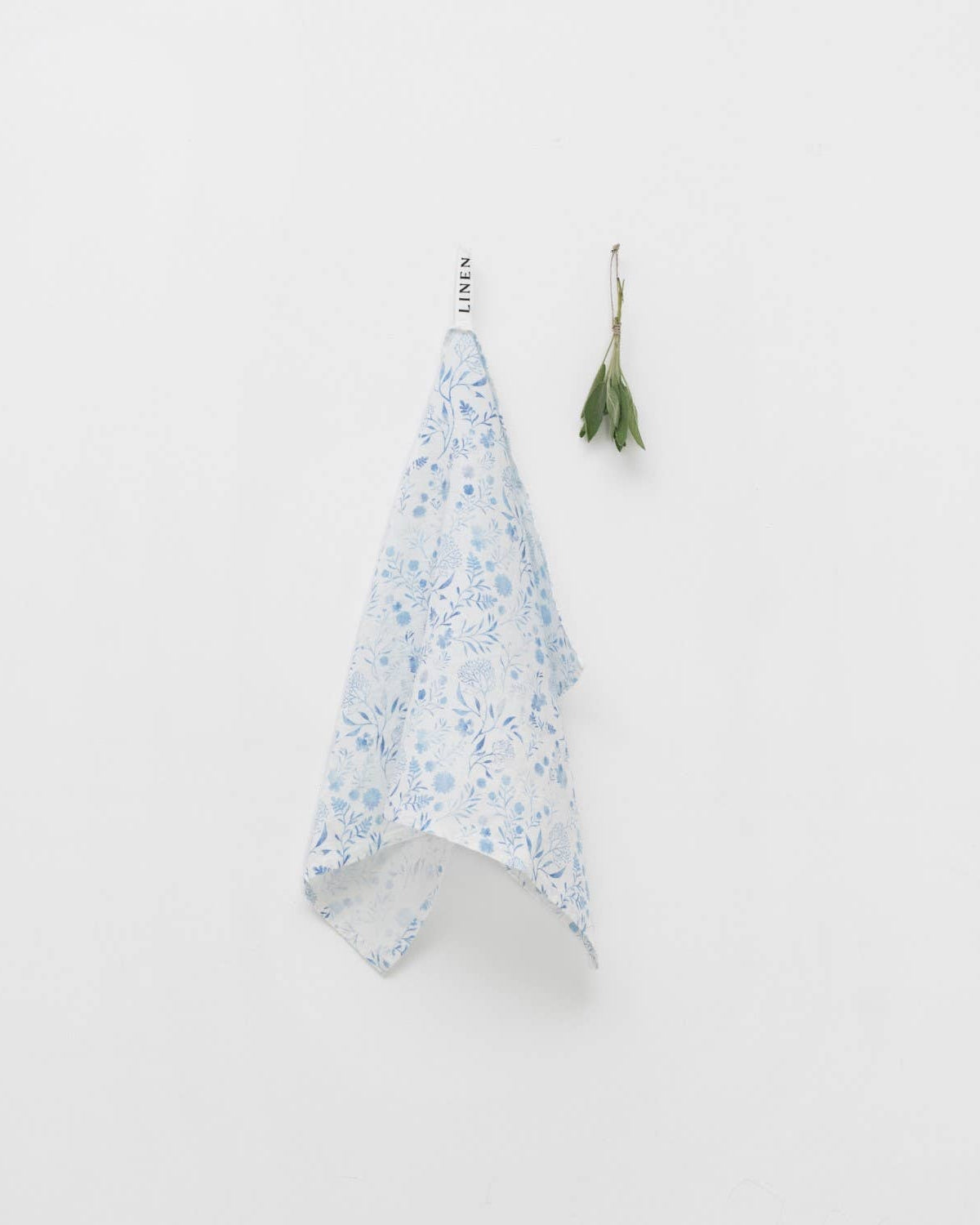 Floral-patterned towel hanging on a hook against a white background