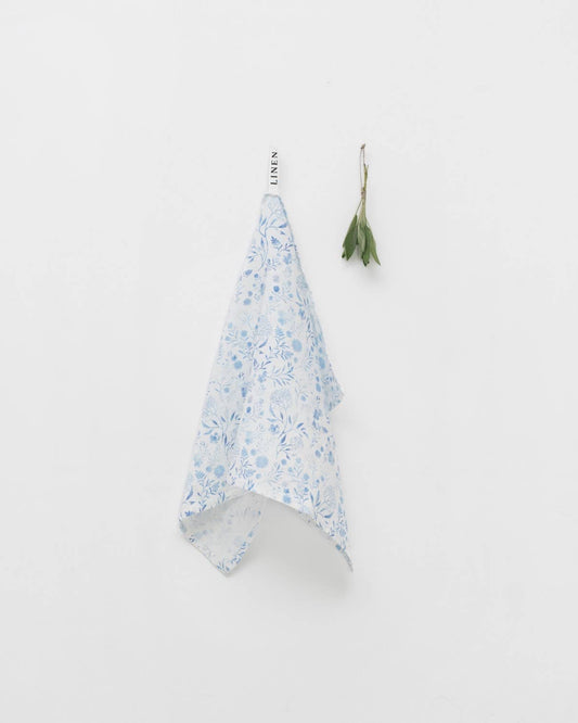 Floral-patterned towel hanging on a hook against a white background
