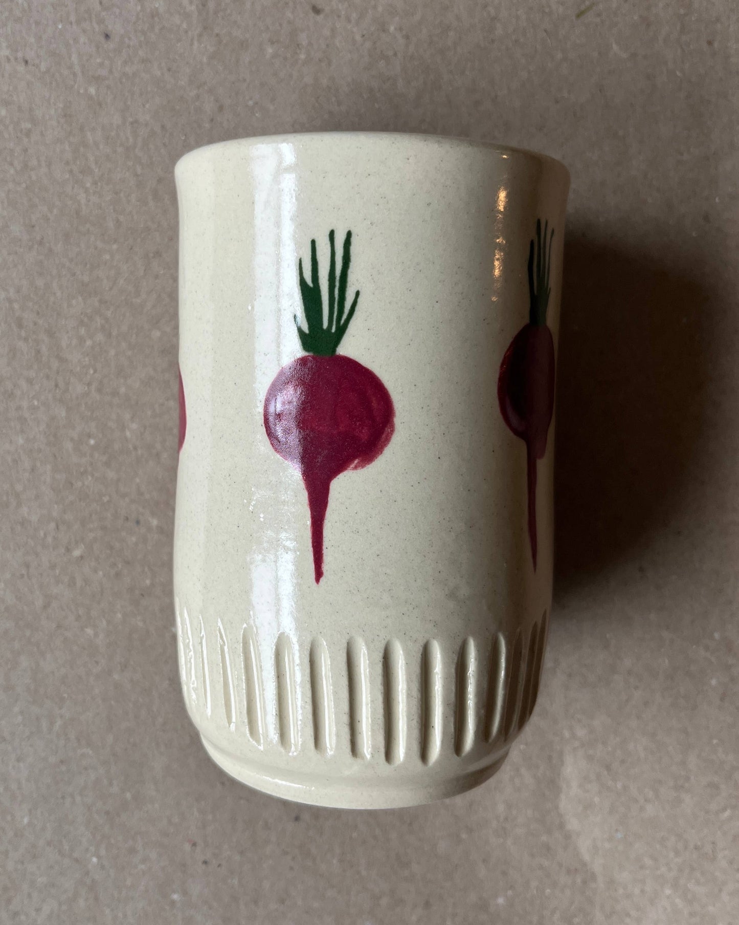 White ceramic cup with red radish design on a gray background