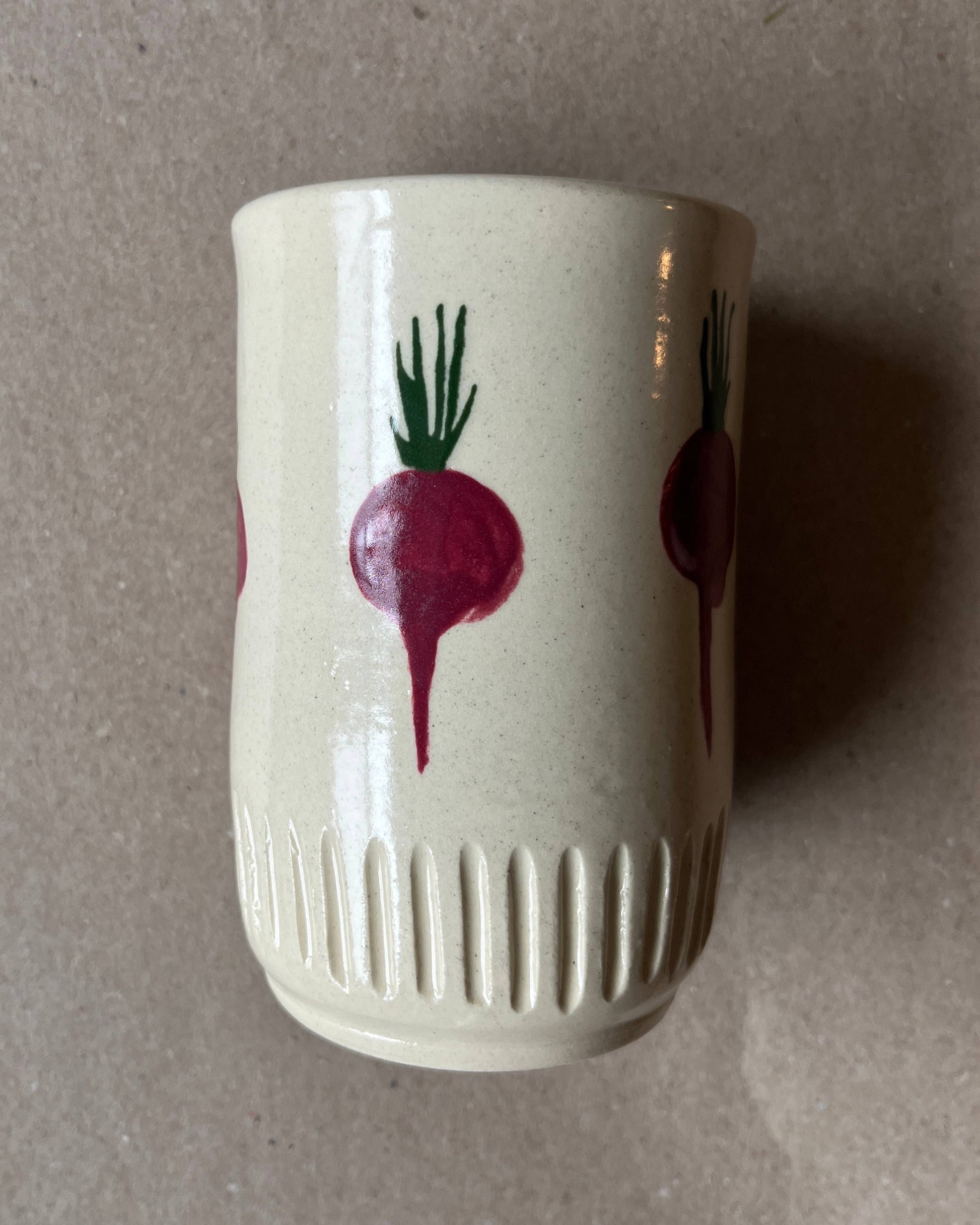 White ceramic cup with red radish design on a gray background