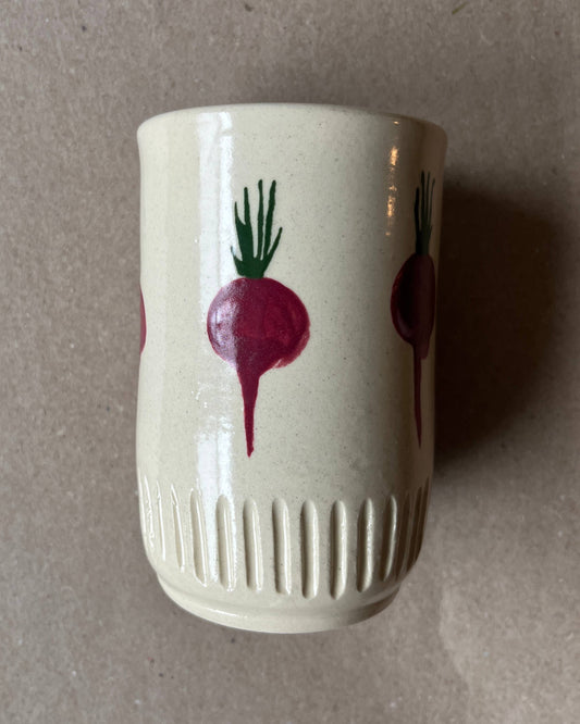 White ceramic cup with red radish design on a gray background