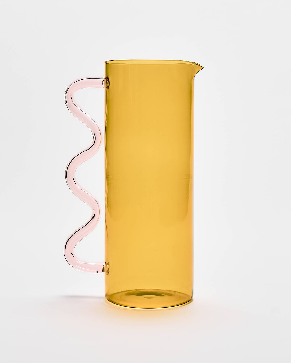 A translucent amber-yellow glass pitcher with a wavy, spiral-shaped pink handle, set against a clean white background.