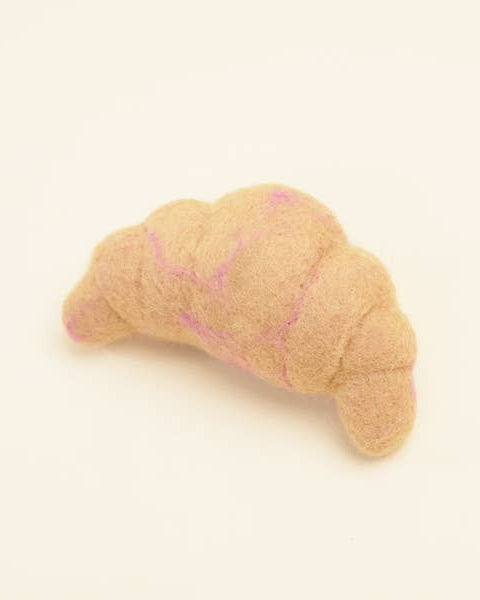 Dog toy shaped like a croissant on a beige background