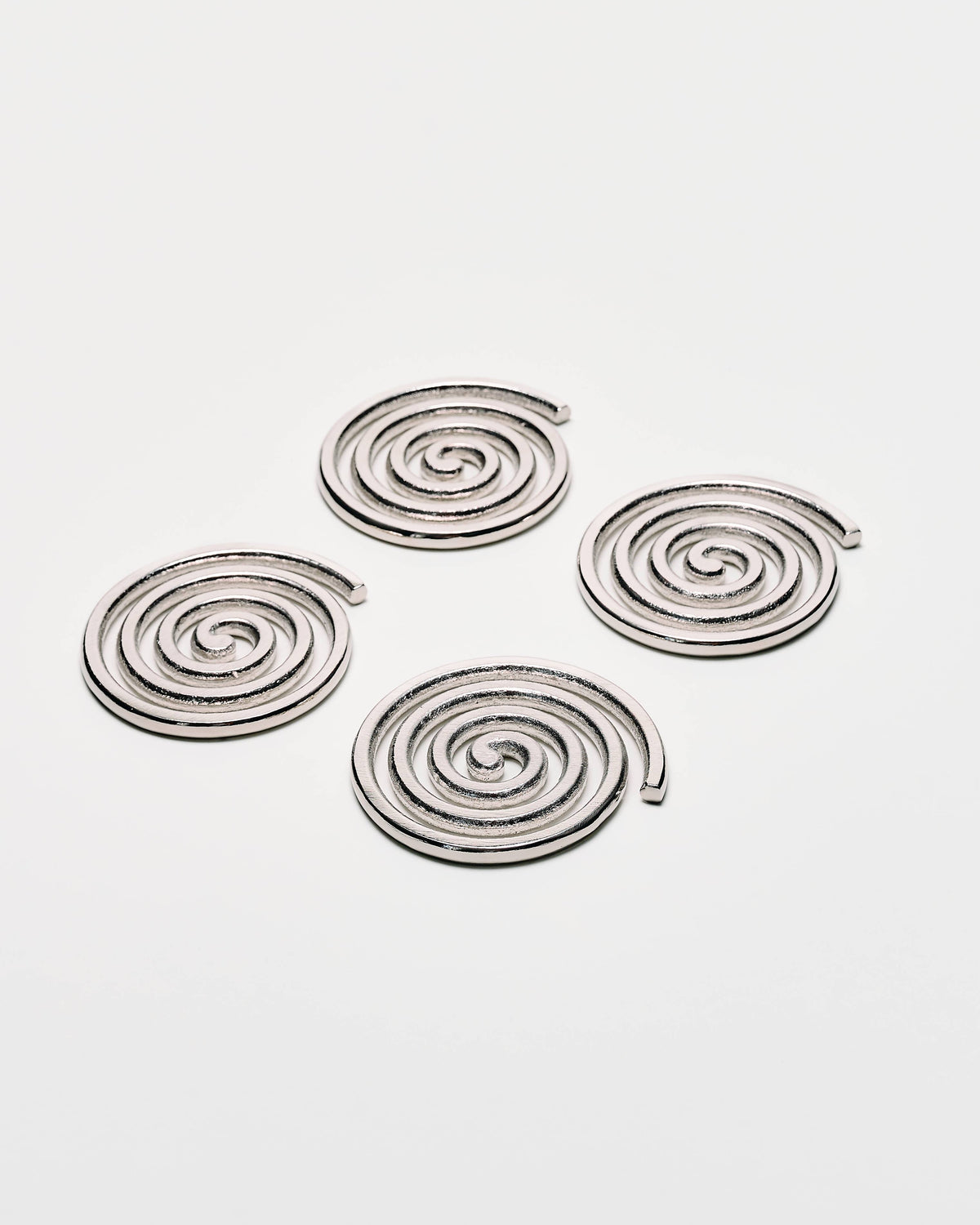 Four spiral-shaped metallic earrings in a silver finish, arranged on a plain light gray background.