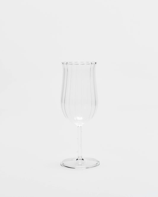 A clear ribbed glass goblet or tumbler with a flared rim and a slender stem, centered on a seamless white background.
