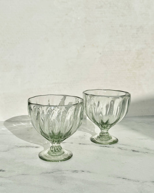 Two clear glass goblets on a marble surface with a light gray background