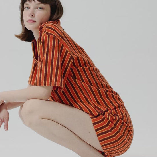 Woman wearing an orange and brown striped dress against a white background