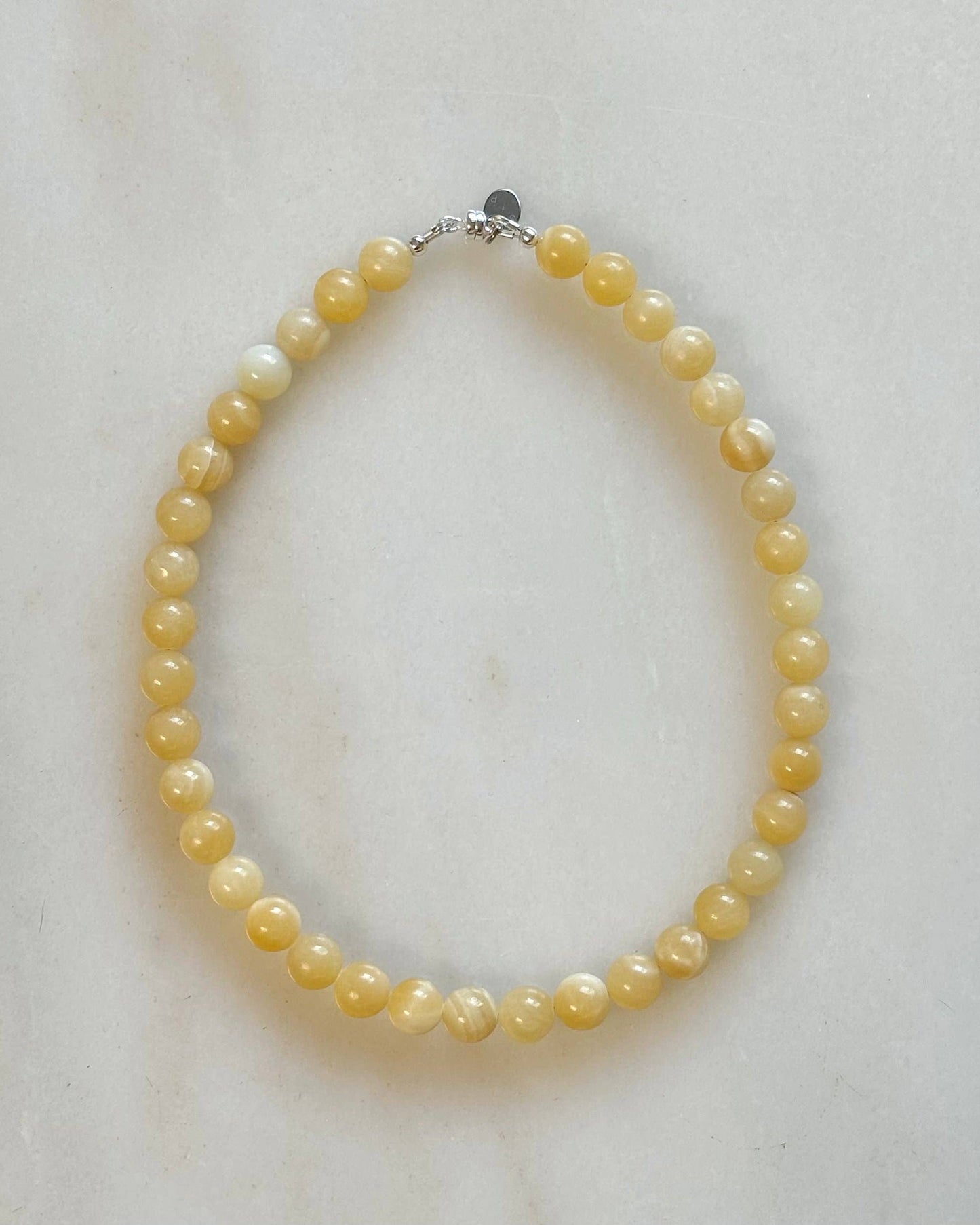 Yellow pearl necklace on a light marble background