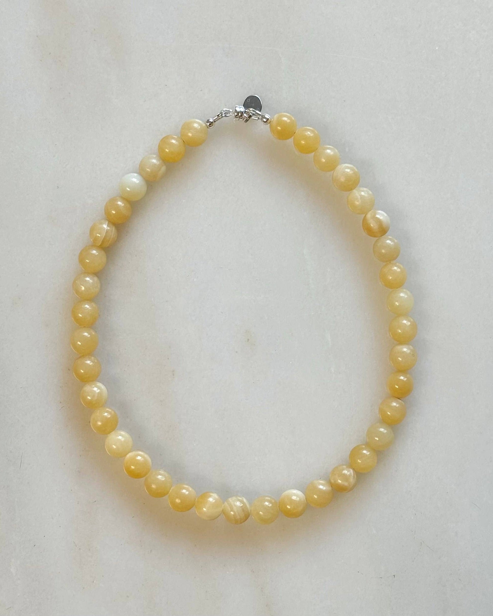 Yellow pearl necklace on a light marble background