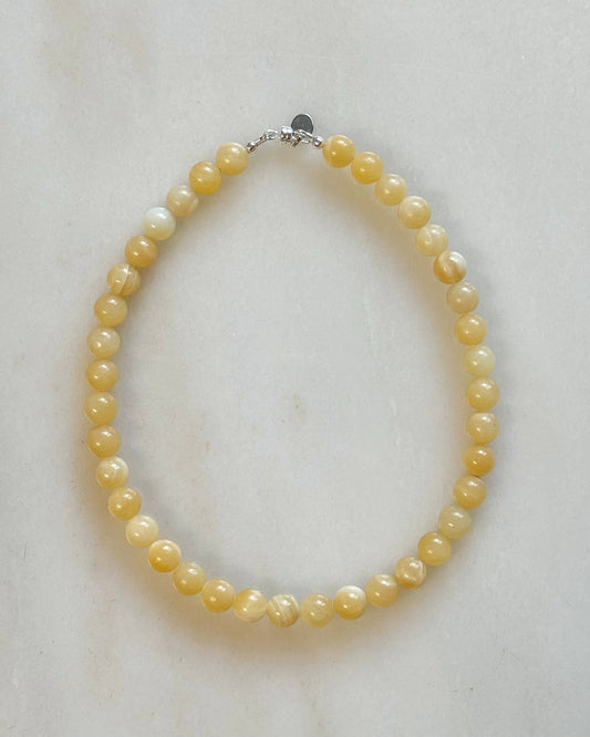 Yellow pearl necklace on a light marble background
