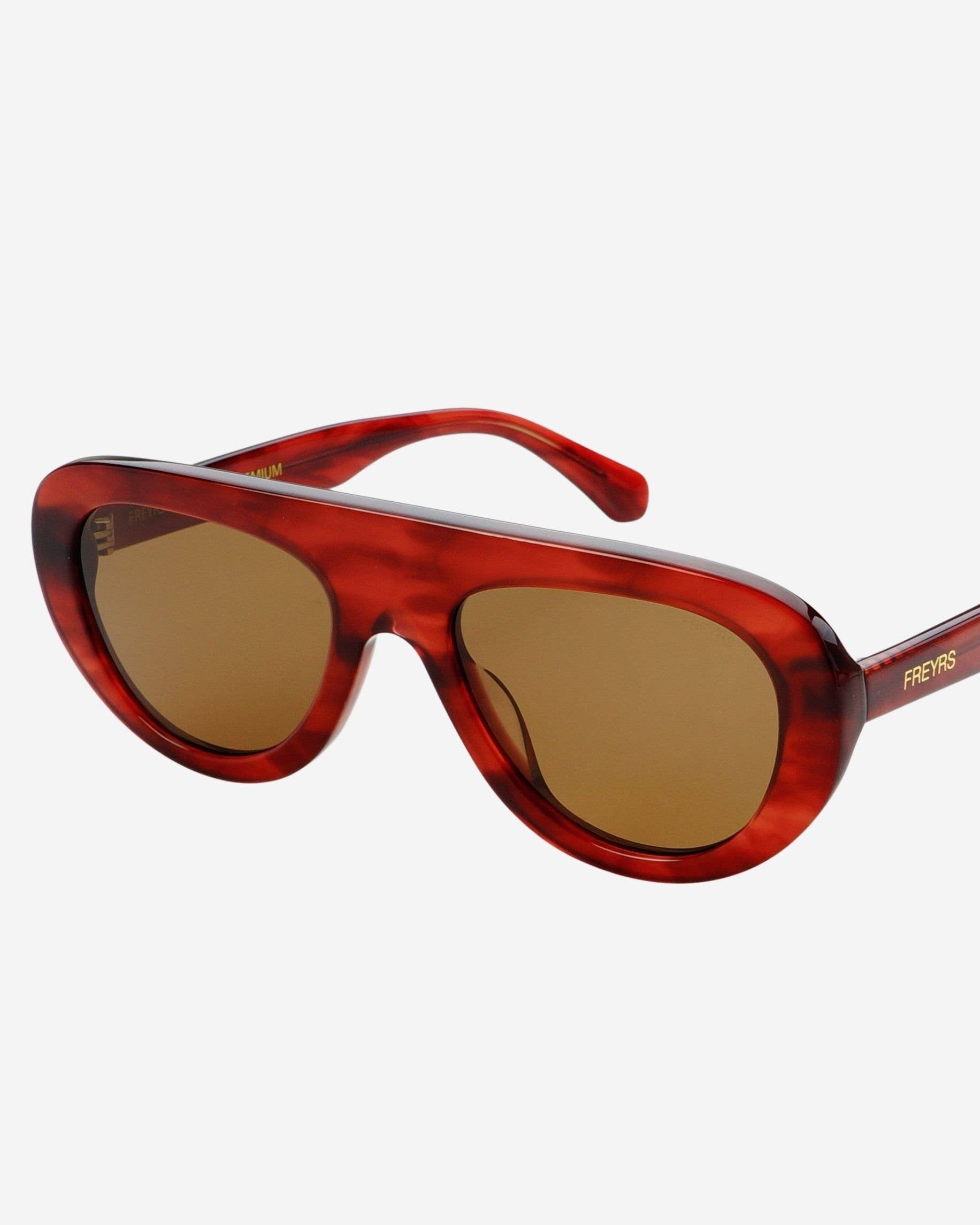 Red sunglasses with brown lenses on a white background
