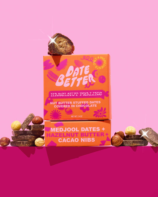 Orange 'Date Better' packaging with dates and hazelnuts on a pink background