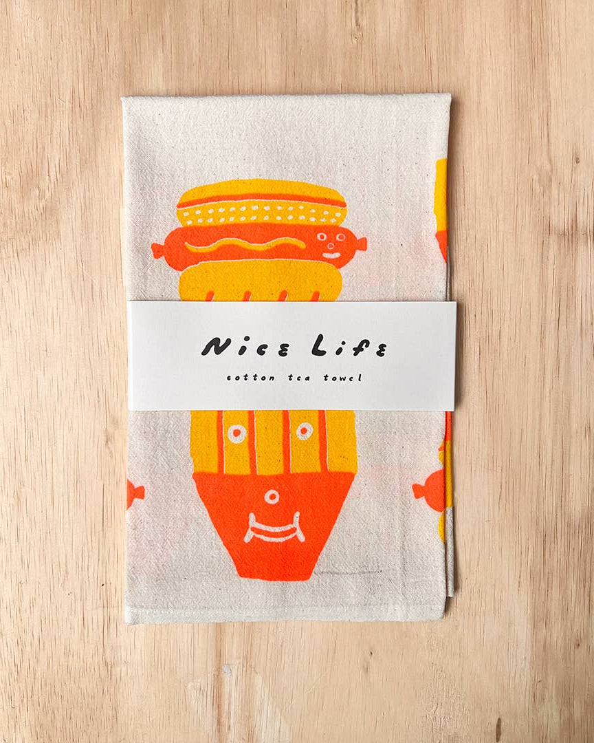 Cotton tea towel with colorful hot dog design on a wooden surface