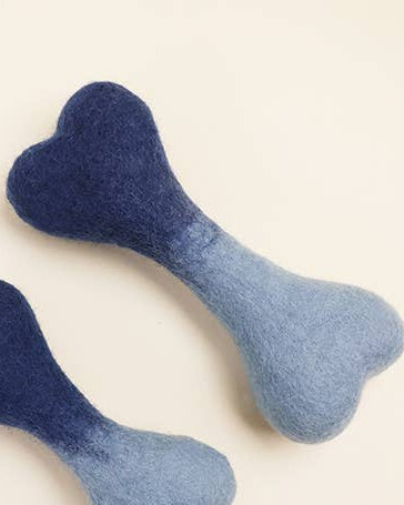 Two blue dog toys shaped like bones on a beige background