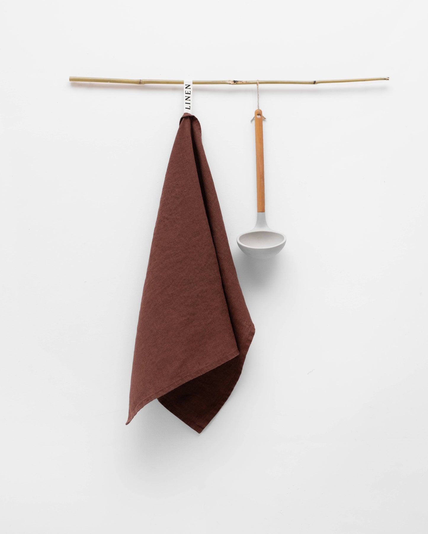 Brown towel hanging on a wooden rack against a white background
