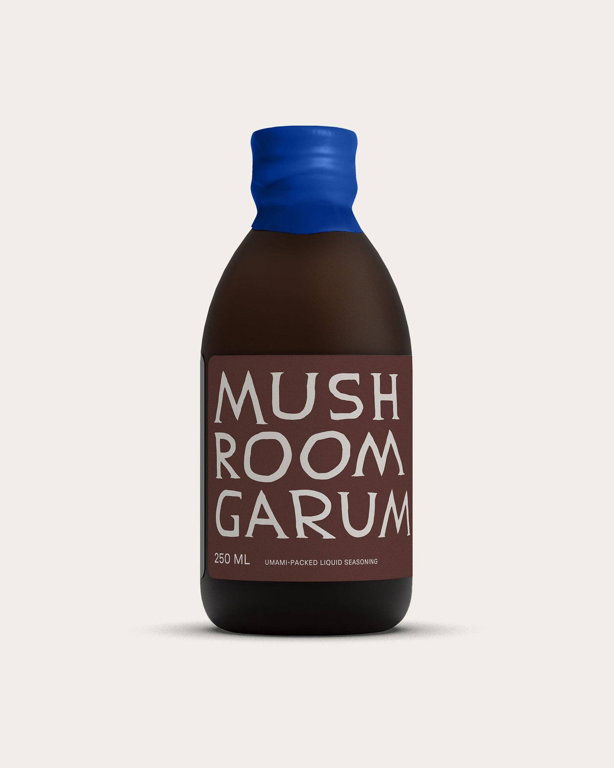Bottle of Mushroom Garum with a blue cap on a light gray background