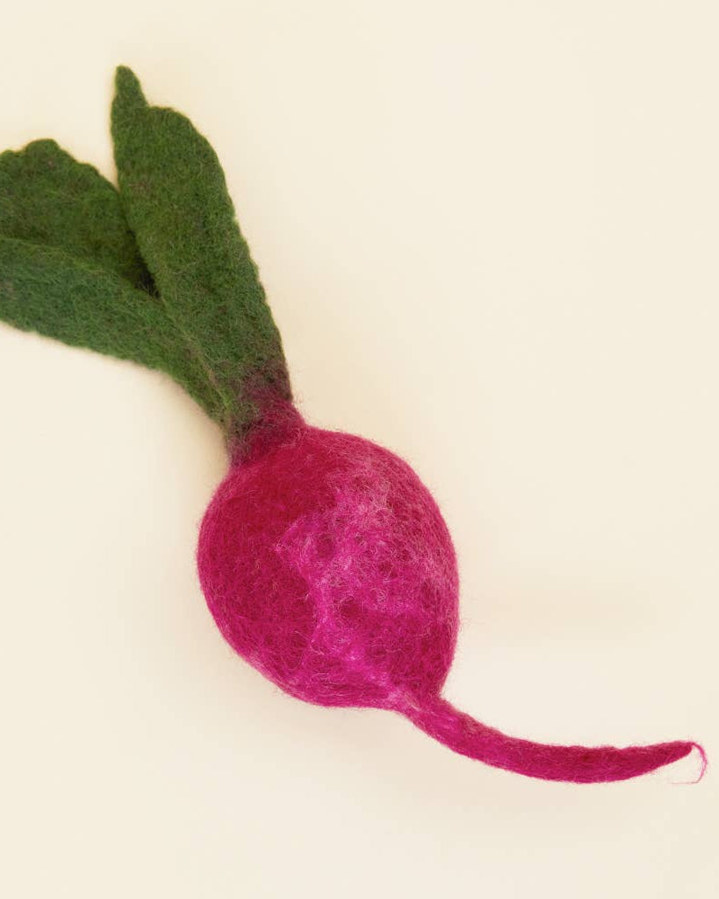Felted pink radish with green leaves on a beige background