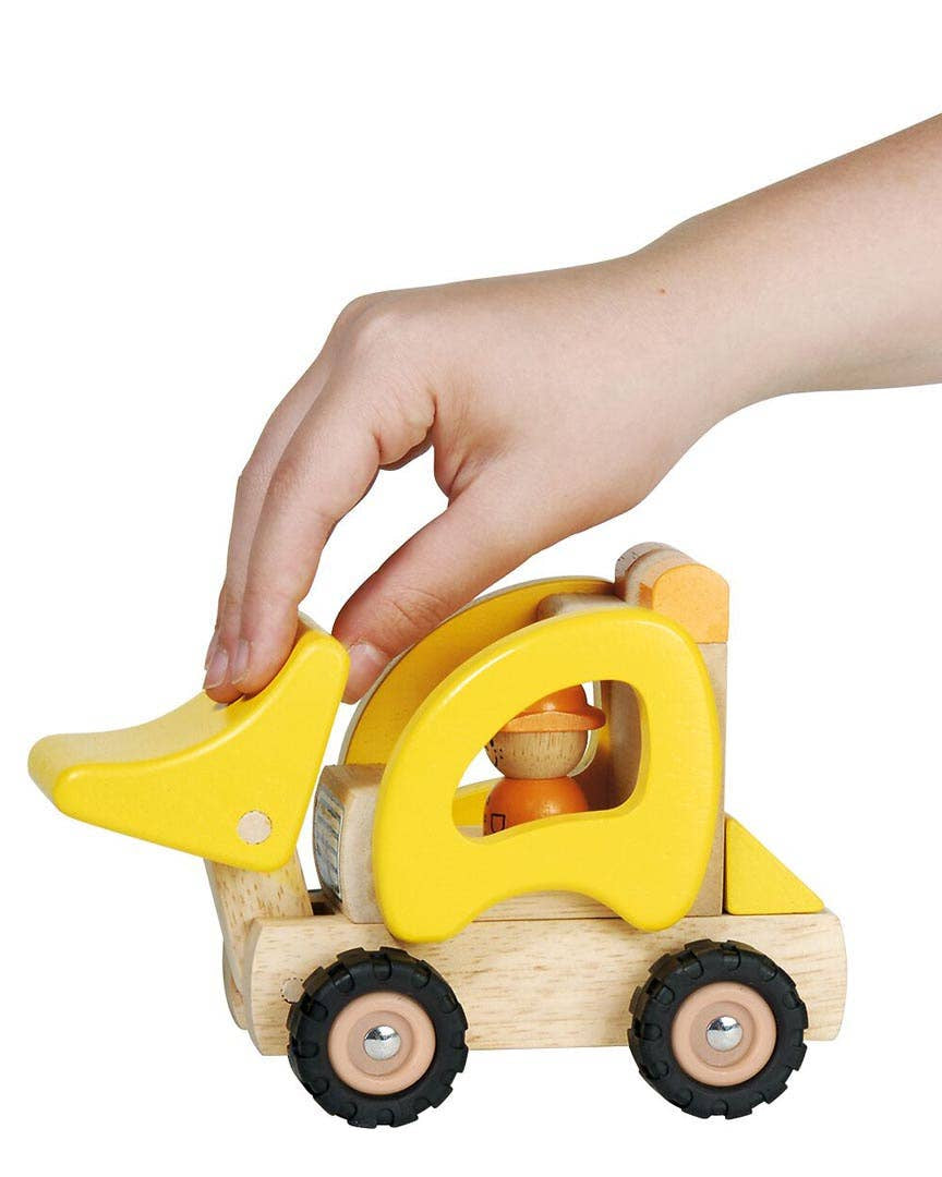 Wooden toy bulldozer with a yellow blade being held by a hand on a white background
