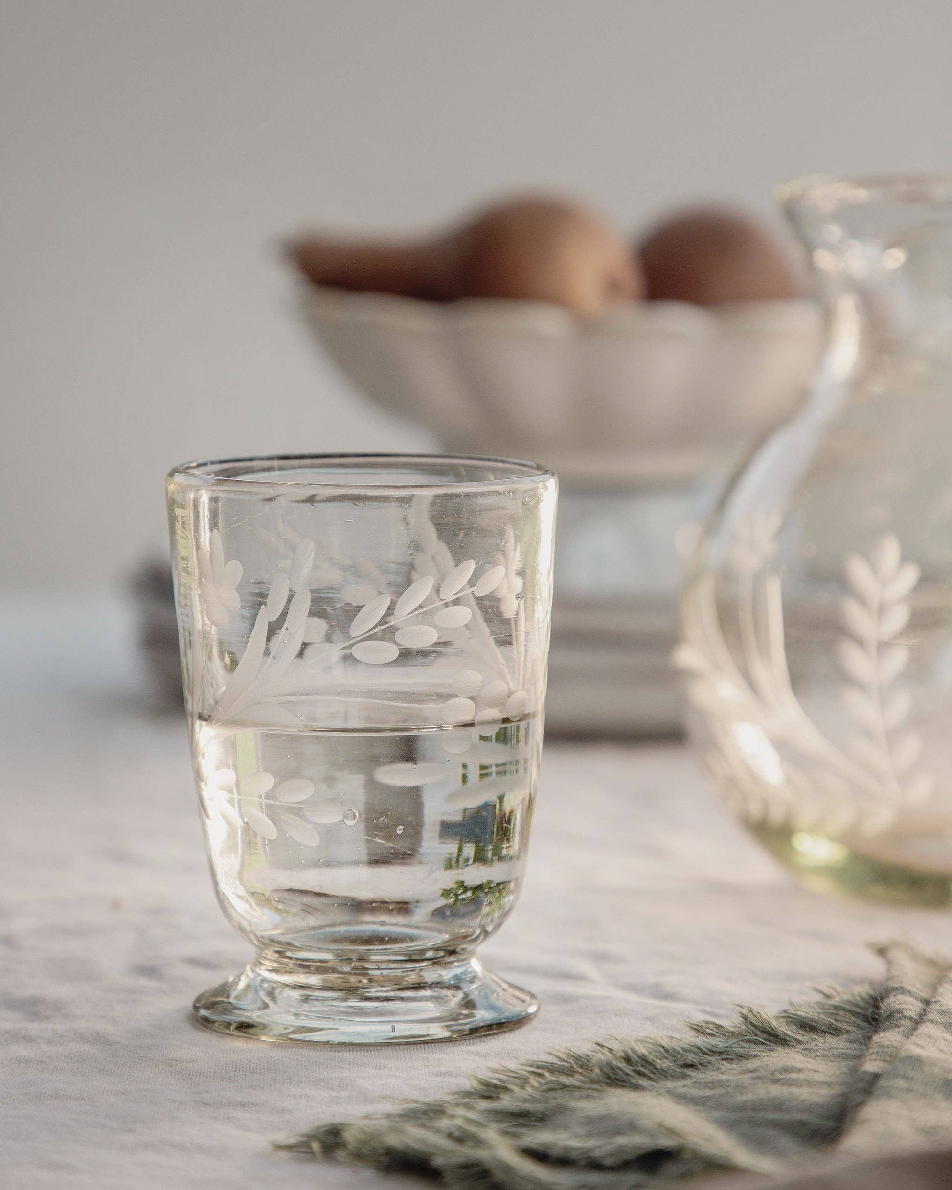 Glass with etched design on a table with a blurred background