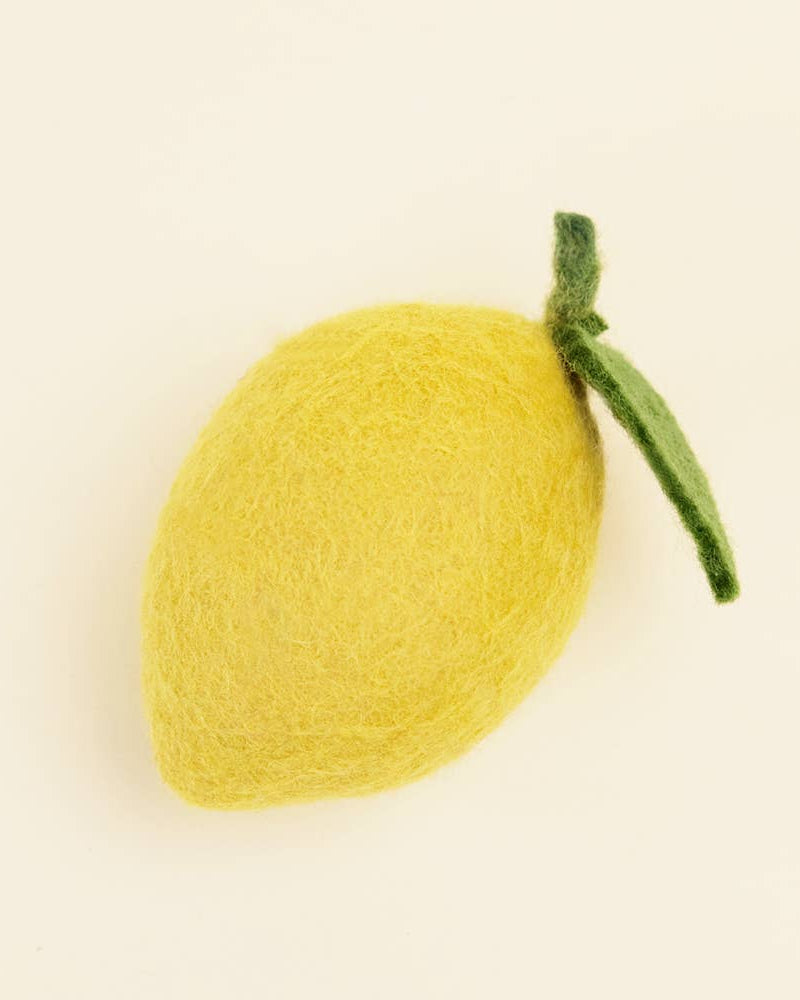 Yellow felt lemon with a green stem on a beige background