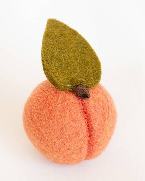 Felted peach with a green leaf on a white background
