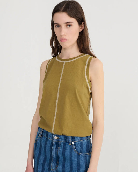 Woman wearing a green sleeveless top with white trim against a plain background