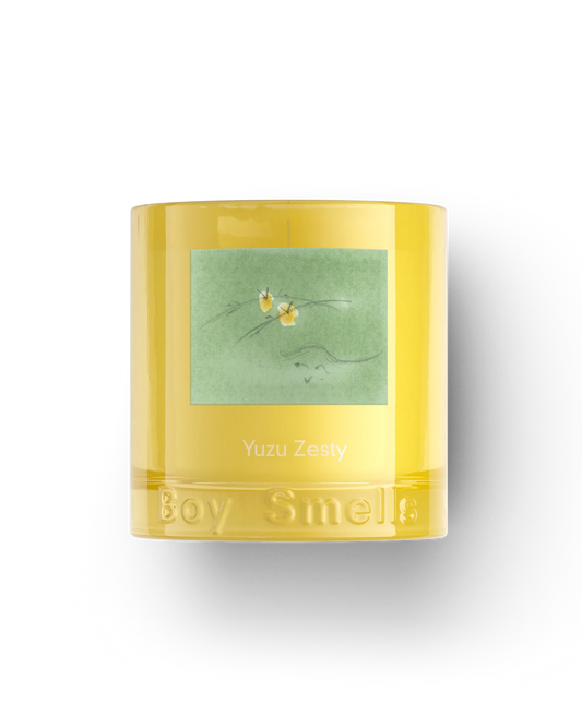 Yellow candle with green label featuring floral design on a white background