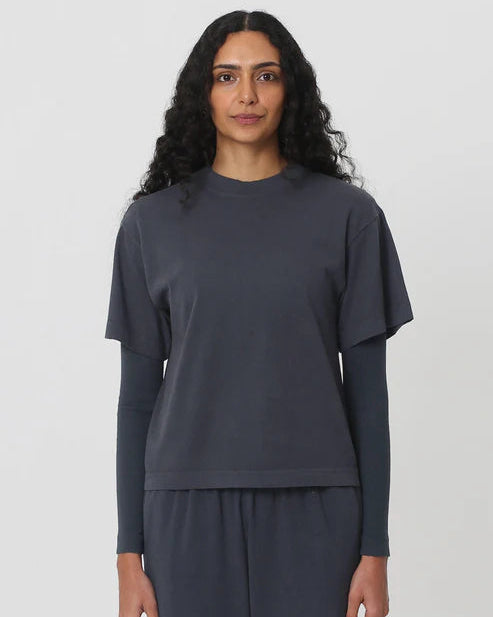 Woman wearing a dark gray long-sleeve top and pants on a white background