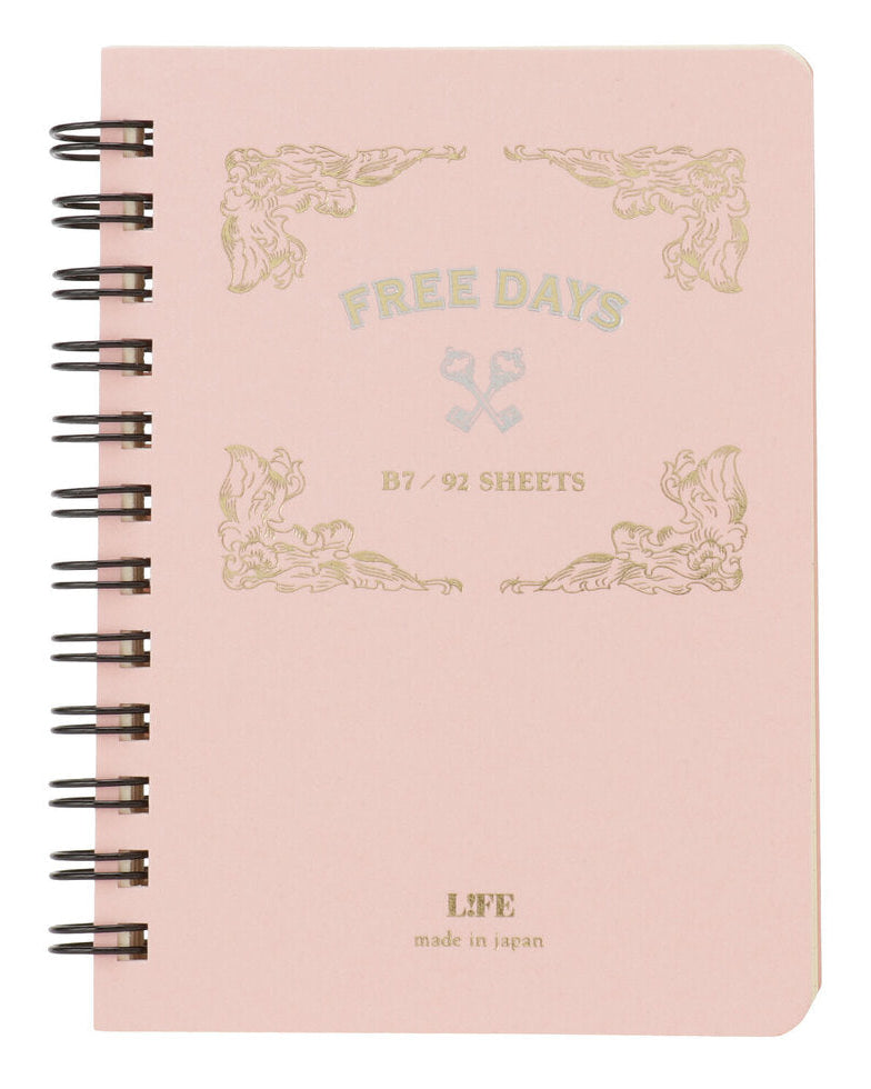 A light pink spiral-bound notebook with black wire binding and gold foil decorative text reading 'FREE DAYS' and 'B7 / 92 SHEETS' on the cover.