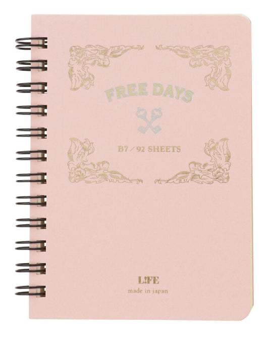 A light pink spiral-bound notebook with black wire binding and gold foil decorative text reading 'FREE DAYS' and 'B7 / 92 SHEETS' on the cover.