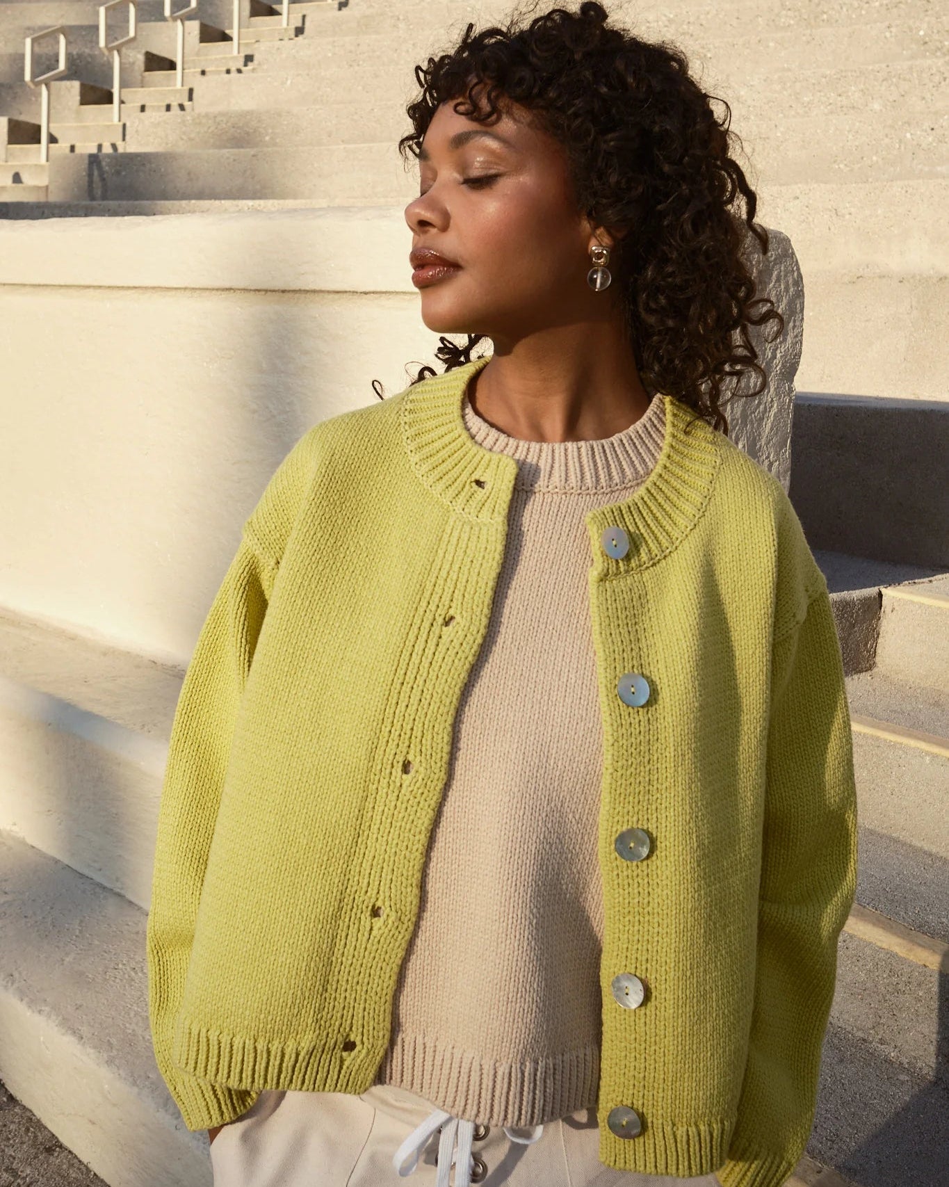 Woman wearing a green cardigan on stone steps
