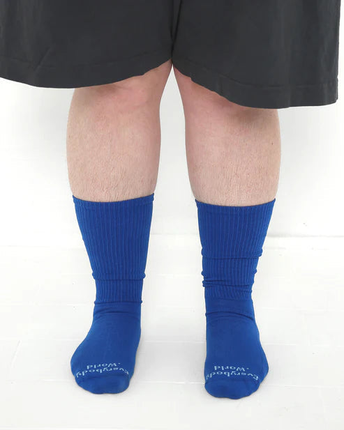 Blue socks worn with black shorts on a white background