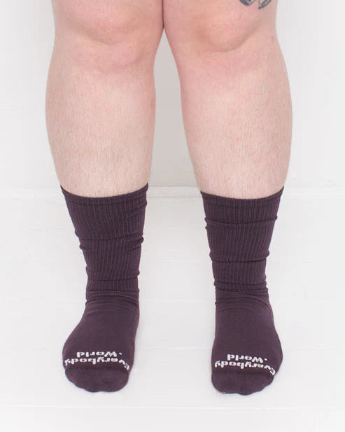 Person wearing dark purple socks with white text on a plain background