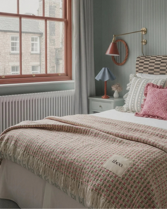 Cozy bedroom with a bed, lamp, and window view.